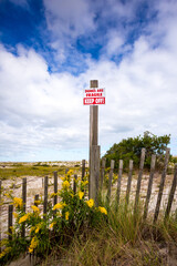 A Keep Off sign and fence on fragile sand dunes
