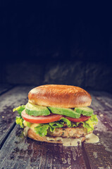 A professional photo of a smash burger topped with creamy avocado, featuring a seared juicy patty, melted cheese, fresh veggies, and a toasted bun, styled to highlight its vibrant, flavorful appeal