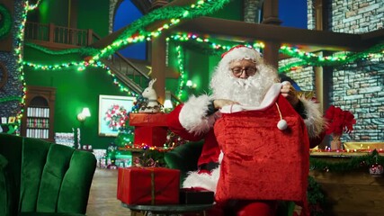 Man dressed as Santa Claus loading red bag with packages, delivering gifts to children on Christmas Eve, making their dreams come true. Entertainer wearing fake beard preparing Xmas presents, camera A