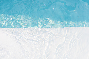 Blue water with ripples on the surface. Defocus blurred transparent blue colored clear calm water surface texture with splashes and bubbles. Water waves with shining pattern texture background.