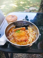 A large portion of spicy miso ramen with slices chicken katsu served in stainless bowl