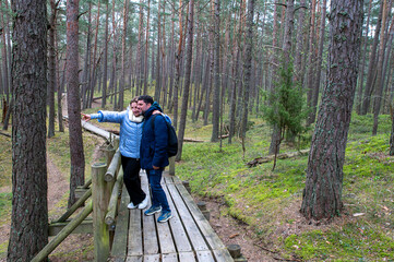Middle-aged Couple Walking and Talking on Wooden Path in Pine Forest