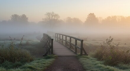 Wooden bridge crossing foggy landscape at sunrise in autumn  