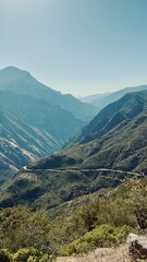 Naklejka premium Expansive view of the Sierra Nevada mountain range with rugged forested valleys and rocky peaks under a clear blue summer sky