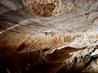 Dramatic rock formations inside a natural cave, lit to reveal intricate textures and layered contours shaped over thousands of years
