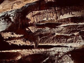 Dramatic rock formations inside a natural cave, lit to reveal intricate textures and layered...