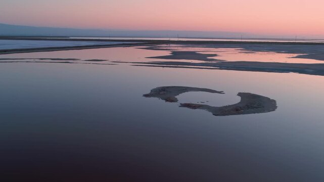 Aerial view of San Francisco Bay Salt Ponds, Fremont, California, USA, at sunset. The ponds are used for salt production, and the different colors indicate varying salinity levels.