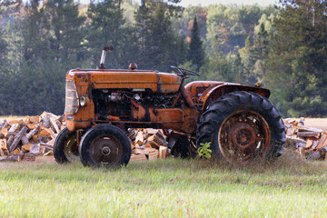 Side view of vintage orange agricultural tractor getting wet in the rain in Ontario Canada