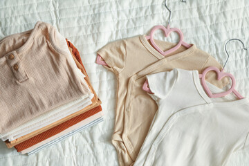 Many clean baby clothes on bed, flat lay