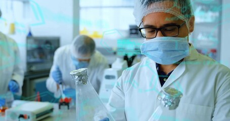 Mid adult scientist wearing lab coat holding Erlenmeyer flasks in lab, with pipette and centrifuge