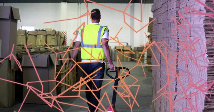 Walking worker wearing safety vest maneuvering pallet jack in warehouse aisle, with cardboard boxes