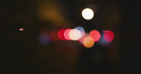 Displaying blurred bokeh lights on urban street at night, featuring red white and orange light orbs