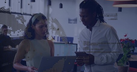 Hispanic woman with headband and man collaborating at desk in office using laptop and tablet