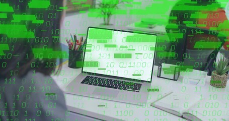 Entering code on silver laptop computer at home office workspace, with green binary overlay