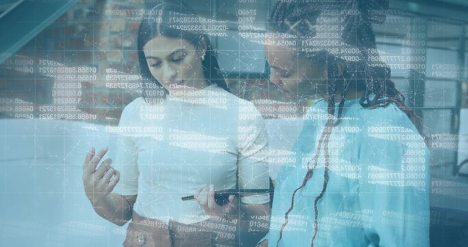 Two coworkers in business attire analyzing code overlay on tablet with stylus in open-plan office