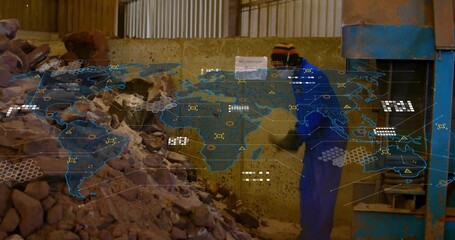 Shoveling worker in coverall feeding rocks into press in workshop, with map overlay, copy space
