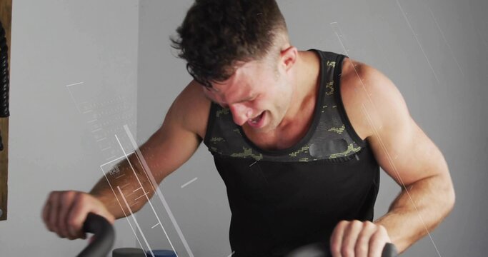 Fototapeta Pedaling muscular enthusiast riding stationary exercise bike in home studio with interface graphics