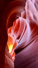 Flowing sandstone formations inside Antelope Canyon in Arizona glowing with purple and pink desert light, sculpted into wave-like patterns and intricate textures that highlight the canyon’s abstract b