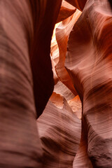 Narrow passage inside Antelope Canyon in Arizona illuminated by desert sunlight, highlighting glowing sandstone walls in warm red tones with wave-like textures and abstract geological shapes