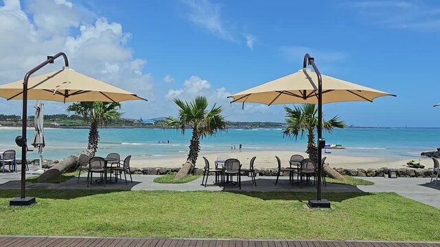 A video of the scenery with parasols on a summer beach with blue sea and clouds
