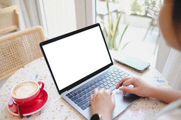 A person working on a laptop with a blank screen at a terrazzo table in a bright, modern cafe with...