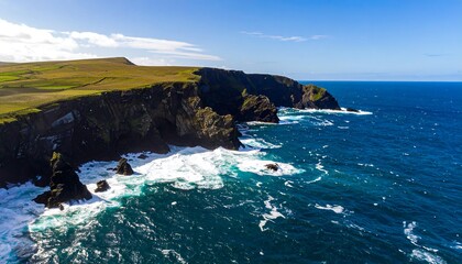 Dramatic coastal cliffs meet a vast ocean under a sunny sky