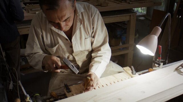 Woodworker hammers chisel while restoring wooden door element