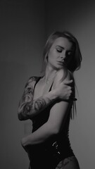 Blonde with a beautiful figure in a black patent leather bodysuit posing in a studio. Studio...