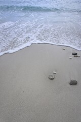 Ocean wave washing sandy beach with stone for coastal nature photography
