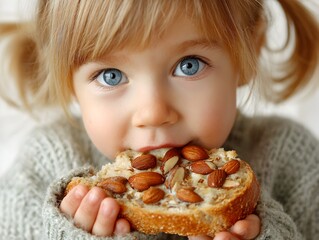 A cute little girl with bright blue eyes enjoys a healthy snack of bread with almond butter topping it now.