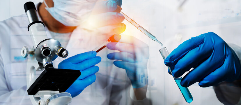 Scientist conducting laboratory experiment with microscope and pipette transferring blue chemical solution