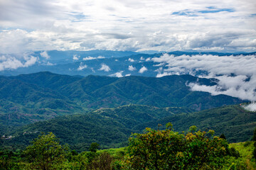 Obraz premium A wide-angle view of the natural scenery of the large mountains, with the wind blowing the mist and some rain falling on the trees. Happiness during the travel to study the resources.