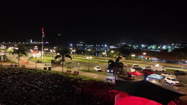 Drone flies along Avenida Amador at night, with streetlights and moving traffic, dark waters on both sides, heading toward Perico and Flamenco Islands in Panama