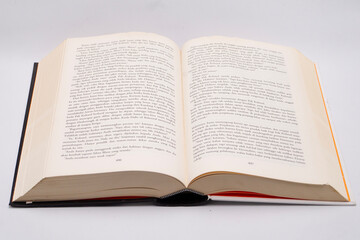 Open Book on White Surface - Close-up of Pages with Text, Black Cover, and Cream Paper.