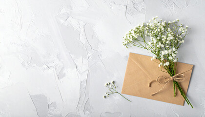 A Delicate Proposition: A sprig of delicate baby's breath rests gently upon a textured gray surface alongside an envelope, tied with a twine bow.