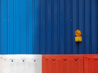 Blue corrugated sheet metal walls with plastic barriers and a safety lamp.