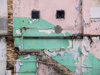 Weathered and damaged walls with peeled off paint and bricks textured surface.