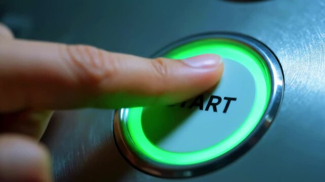 Close-up of a finger pressing a green 'START' button on a metallic surface, symbolizing initiation