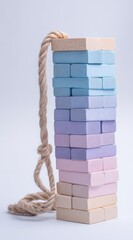 Pastel wooden blocks tower, tied with rope, isolated on white. Abstract representation