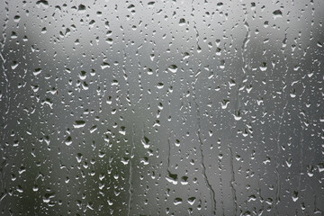 Raindrops cascade down a window pane, creating a beautiful, textured backdrop of nature's elements.