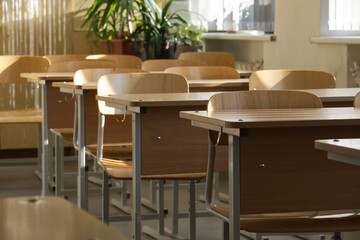 An empty classroom bathed in soft light, with rows of student desks ready for class.