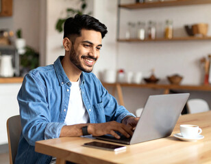Fototapeta premium Cheerful young adult man in casual outfit at cafe, laptop open and coffee on table, smiling as he works, creative freelancer or startup scene, stylish business lifestyle stock photography.