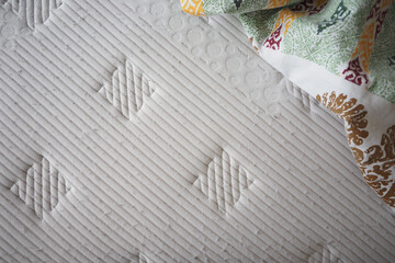 Comfortable mattress with patterned bedding in cozy room