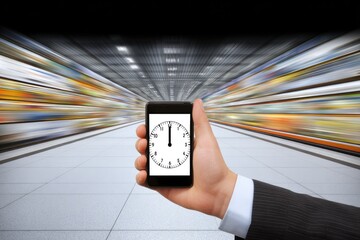 Hand holding smartphone with clock, blurry supermarket background