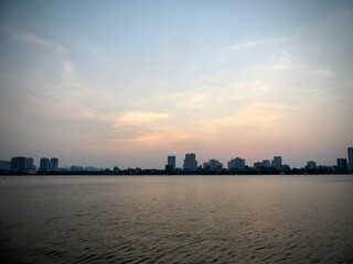Obraz premium Blue-Hour Haze Above West Lake Skyline, Hanoi – Calm Water and Distant High-Rises