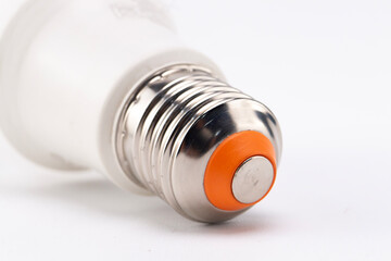 Close-up of a Light Bulb Base with Silver Threads, Orange Insulator, and White Background.