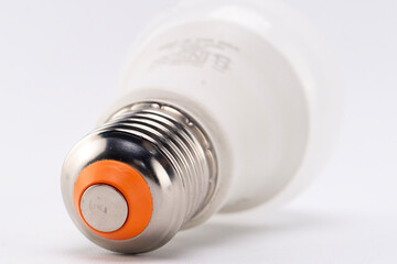 Close-up of a White LED Light Bulb with Silver Base and Orange Accent on White Background.