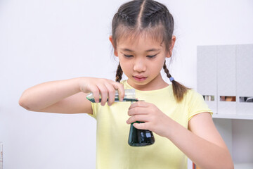 A smiling girl raises two colorful test tubes in each hand as part of a science experiment. Cheerful mood and vibrant setup show excitement for learning through creativity, learning, back to school.