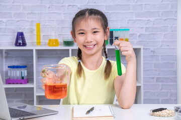 A smiling girl raises two colorful test tubes in each hand as part of a science experiment. Cheerful mood and vibrant setup show excitement for learning through creativity, learning, back to school.