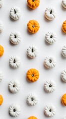 Pattern of mini orange and white pumpkins arranged on a white surface. Top-down, clean look. Minimalist